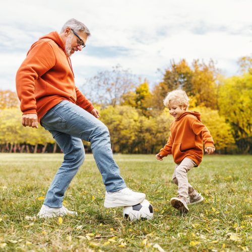 Happy,Family,Grandfather,And,Grandson,Play,Football,On,Lawn,In